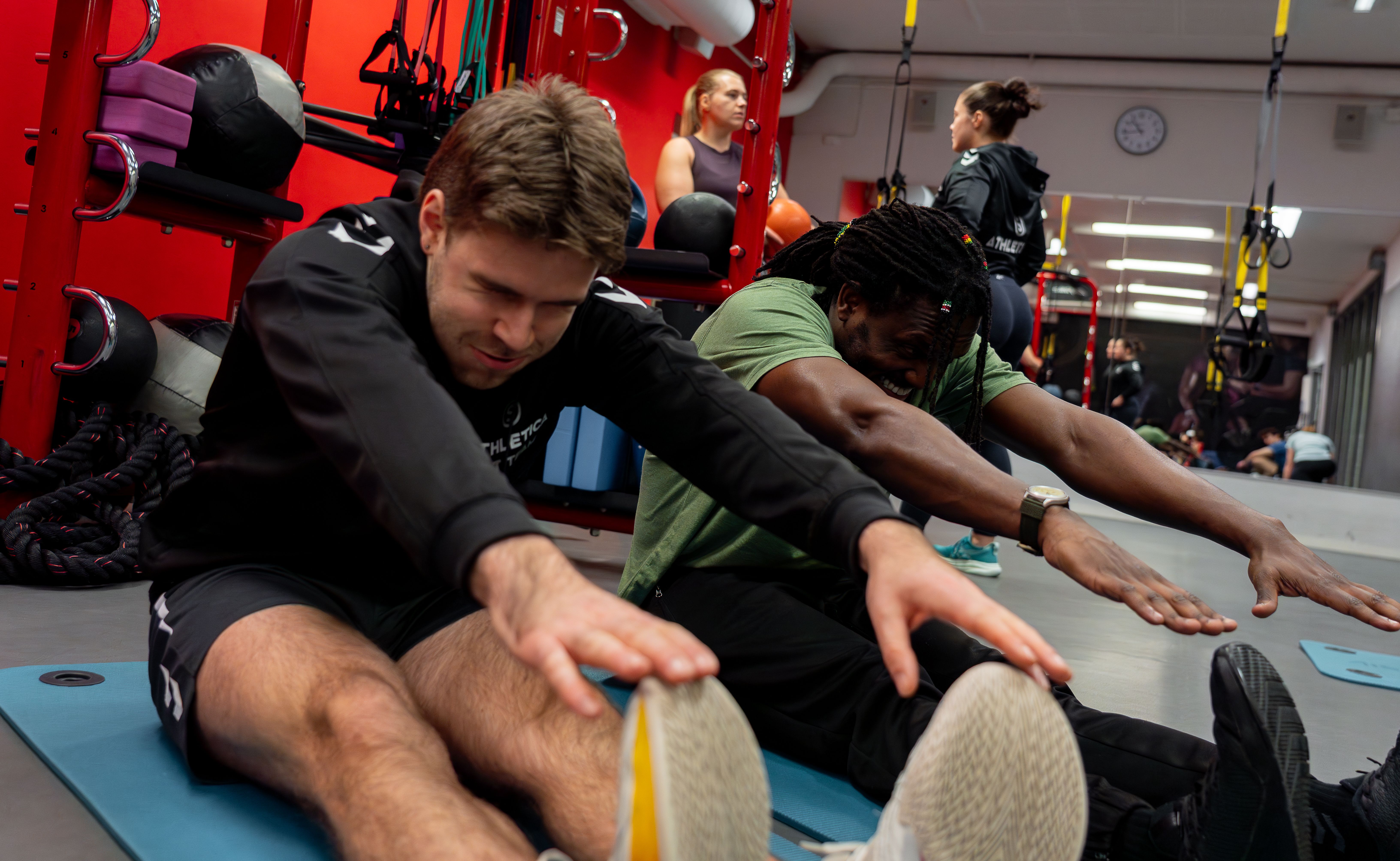 To stk som sitter og tøyer på Athletica Blindern i den funksjonelle treningssonen. 