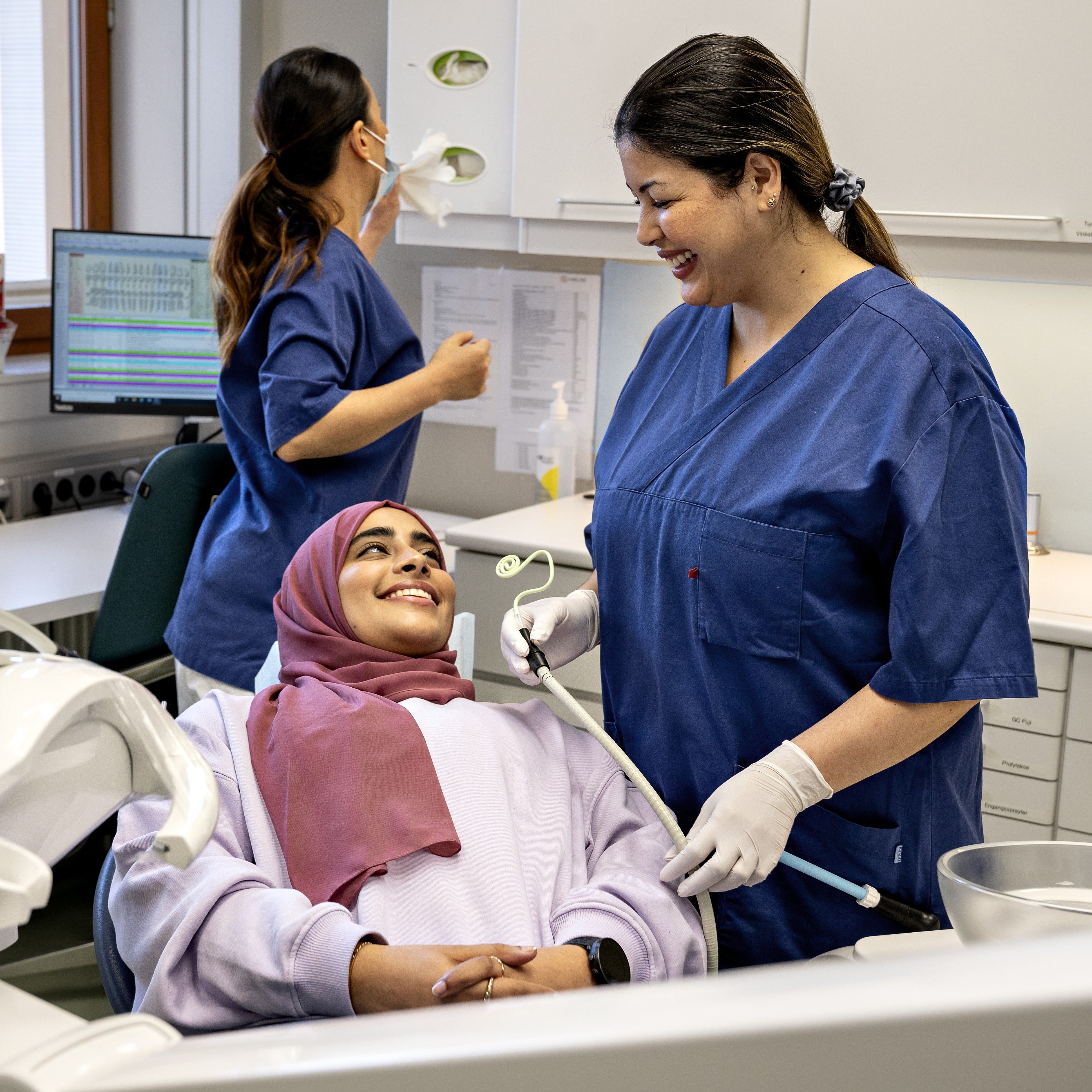 Image of a student in a dental chair smiling at a dentist.