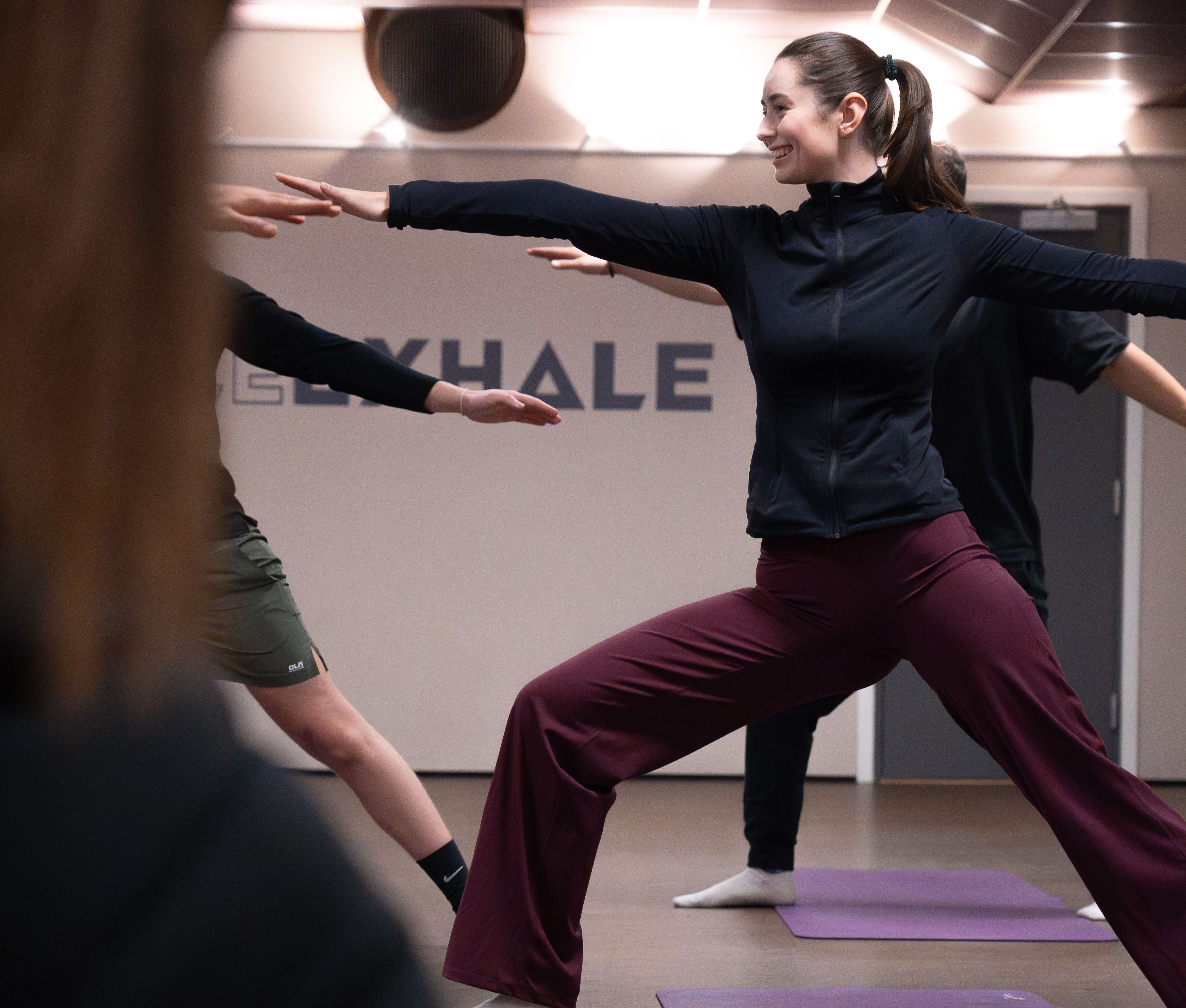 En gruppe gjør yoga på Athletica Centrum med en kvinne i fokus.