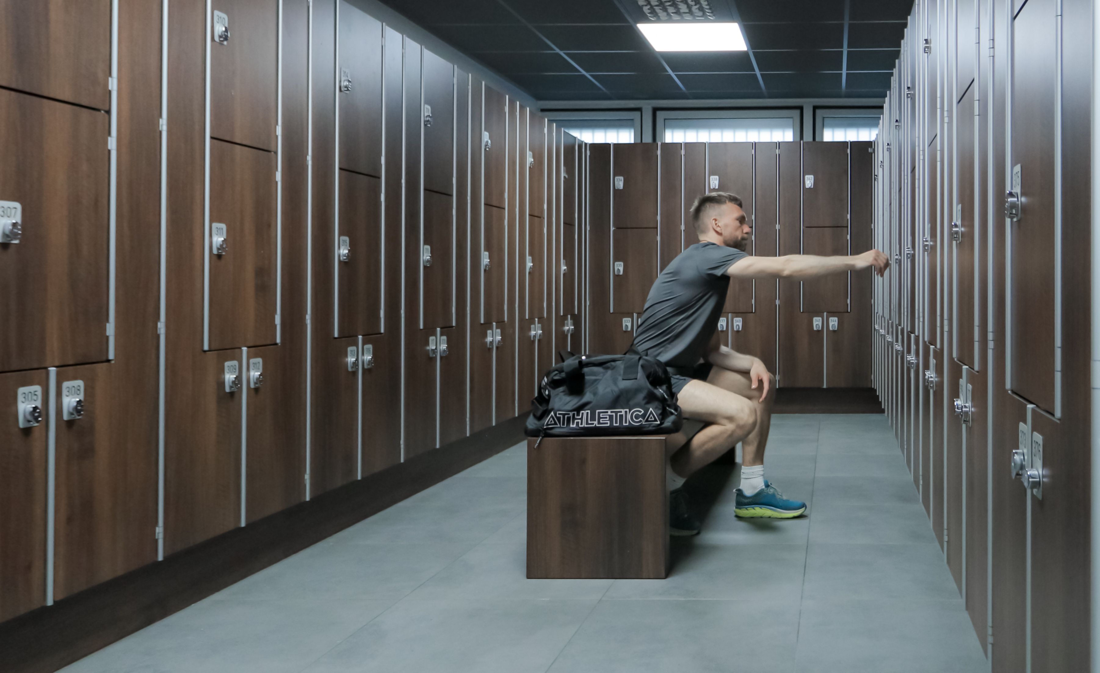En mann som sitter på en benk i herregarderoben på Athletica Centrum. 