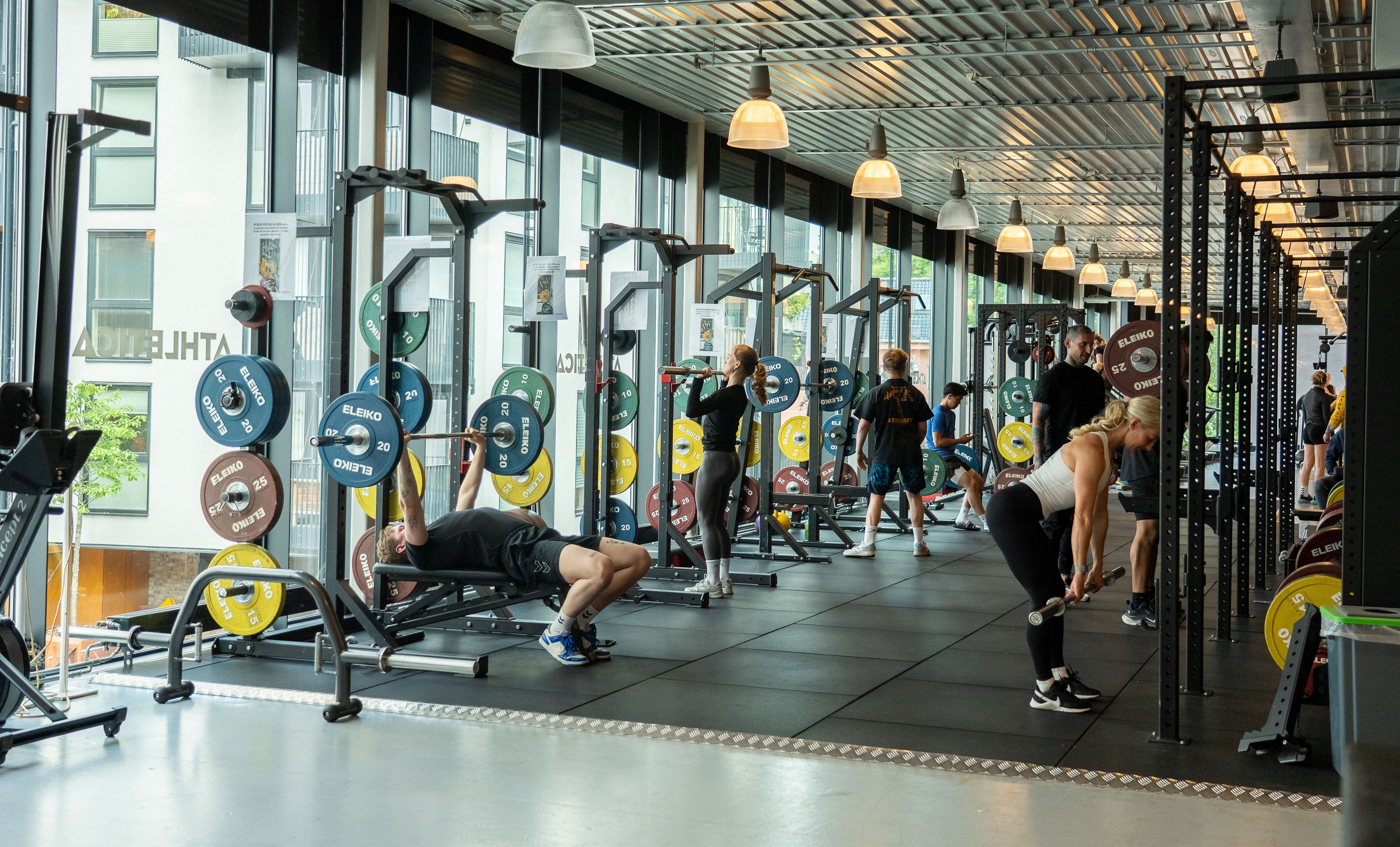 Treningsstudio på Athletica Vulkan med løfteracks, olympiske vektskiver og flere som trener. 