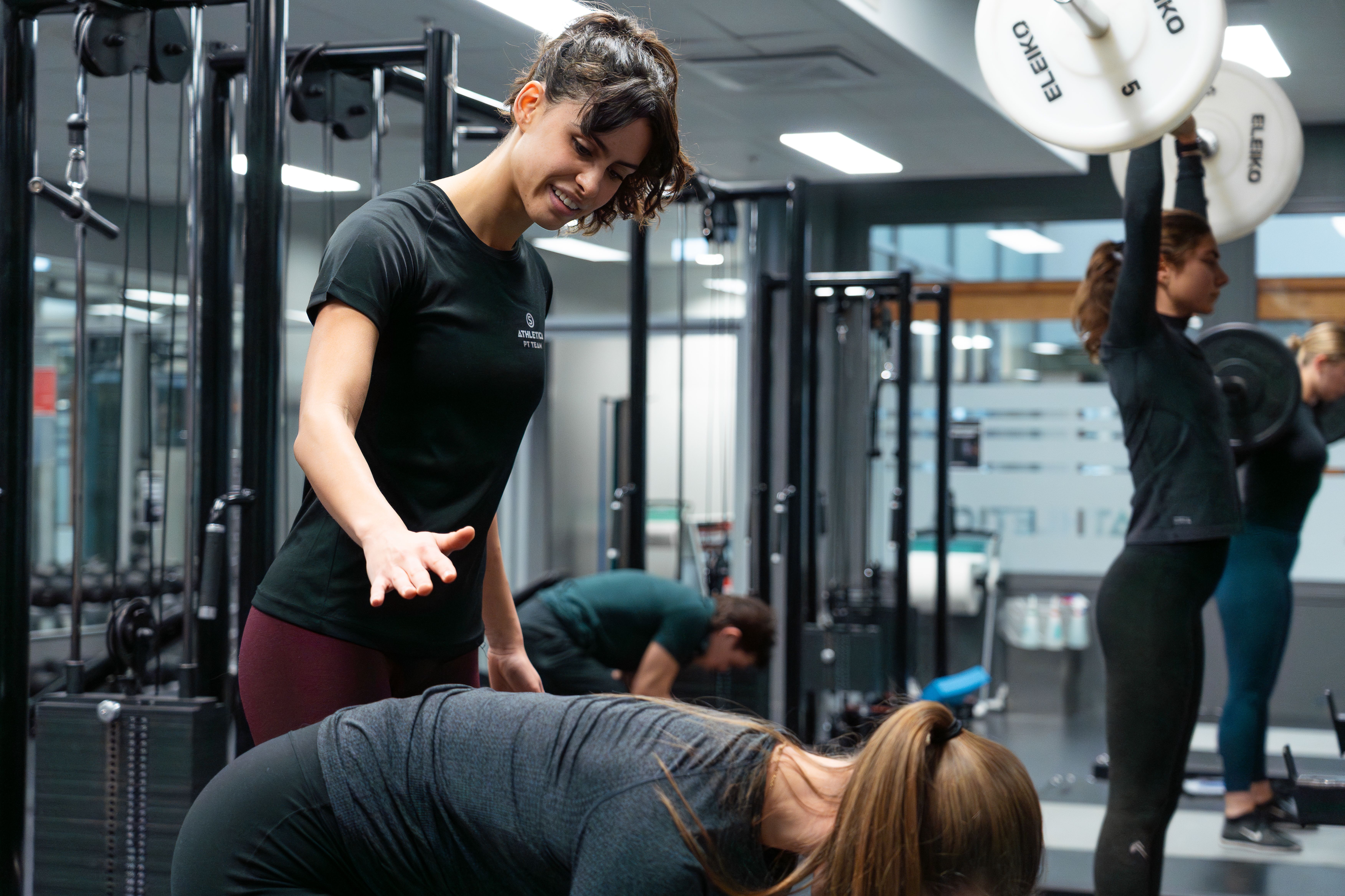 En PT instruerer og støtter en kunde på friveksttrening hos SiO Athletica Nydalen. 