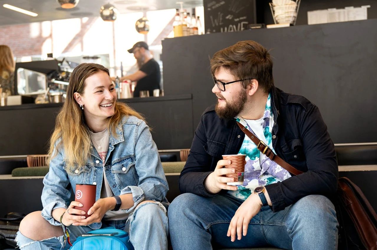 To studenter drikker kaffe sammen på et SiO spisested.