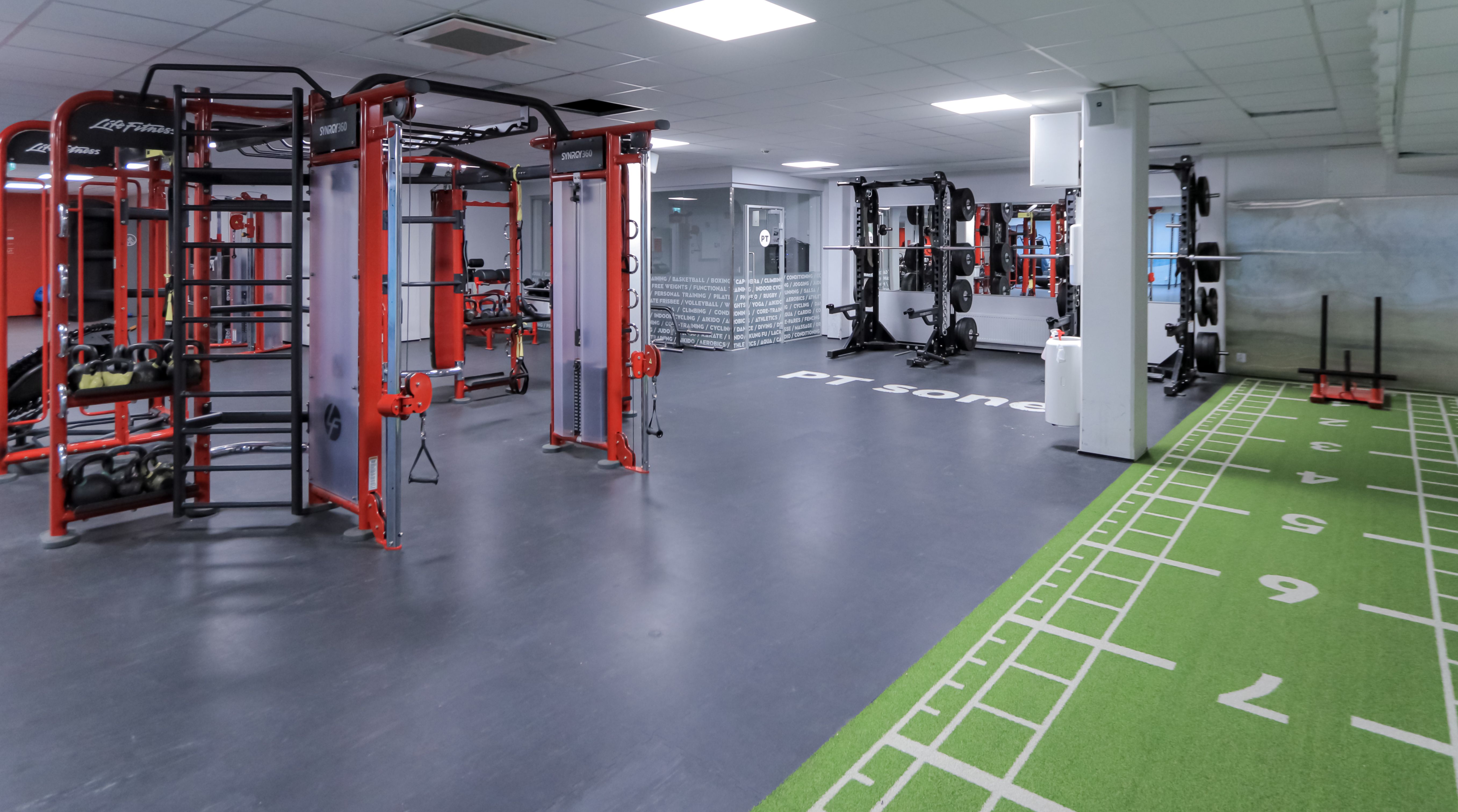 Funksjonell treningssone med turf, cage, apparater og racks i kjelleren på Athletica Centrum. 
