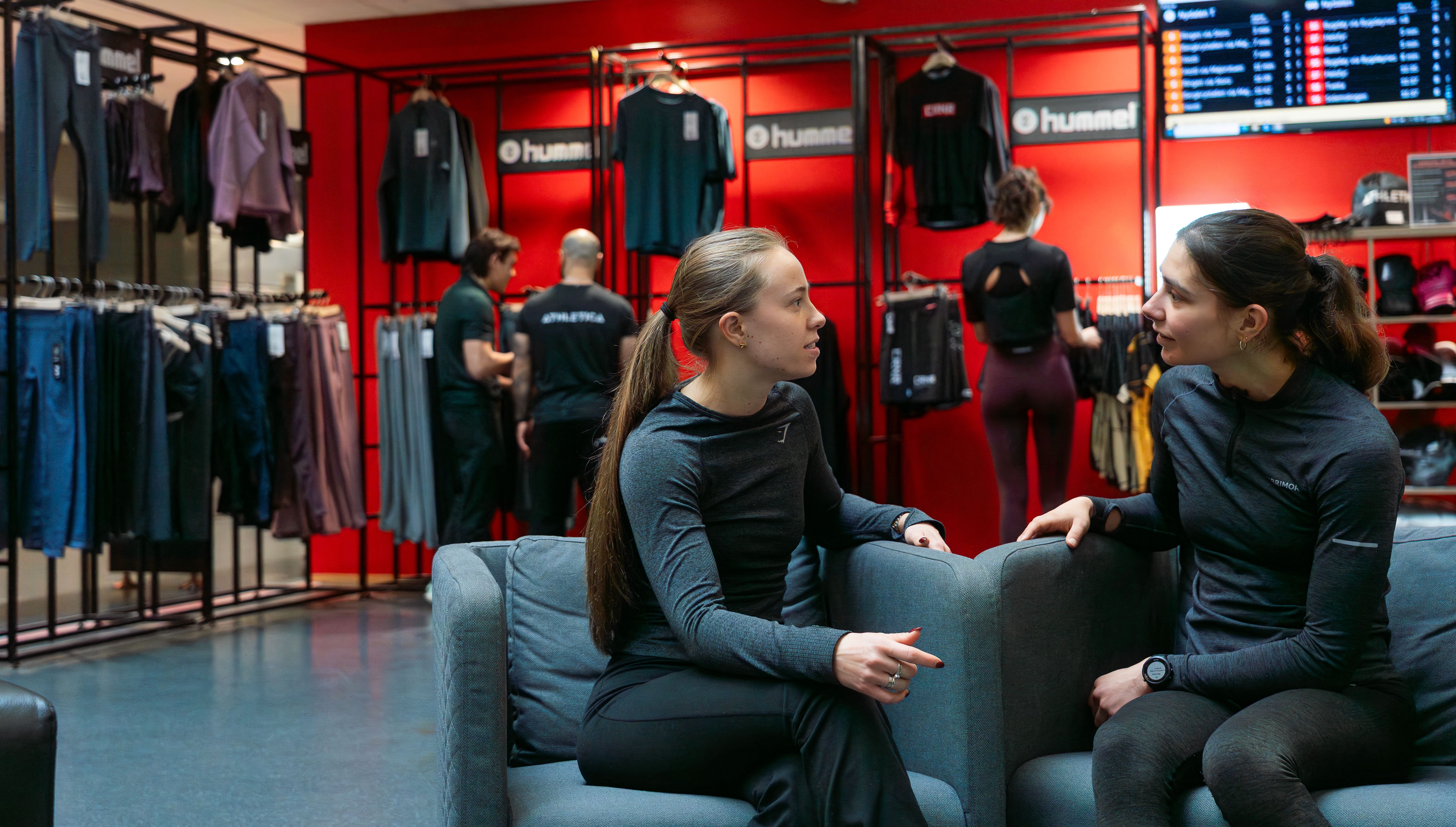 To jenter sitter i mingleområdet til SiO Athletica Nydalen og prater. 