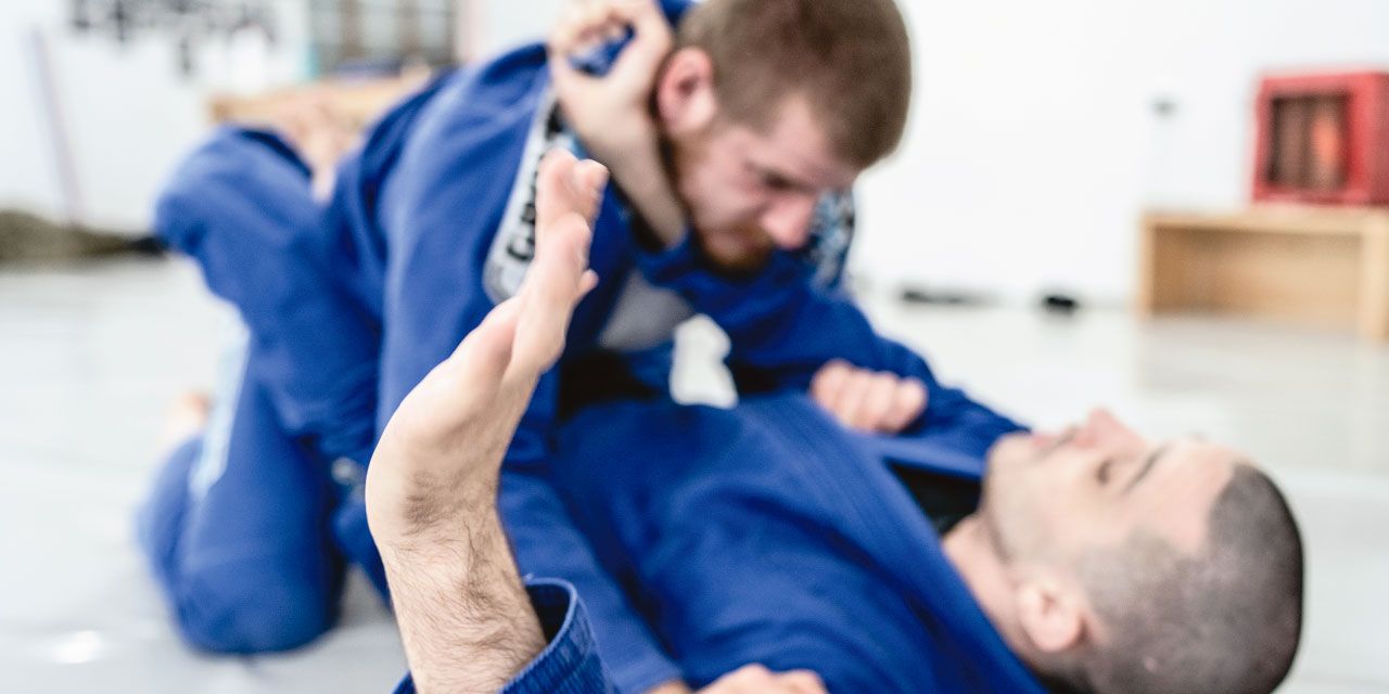 To menn sparrer i BJJ med gi-drakt på.