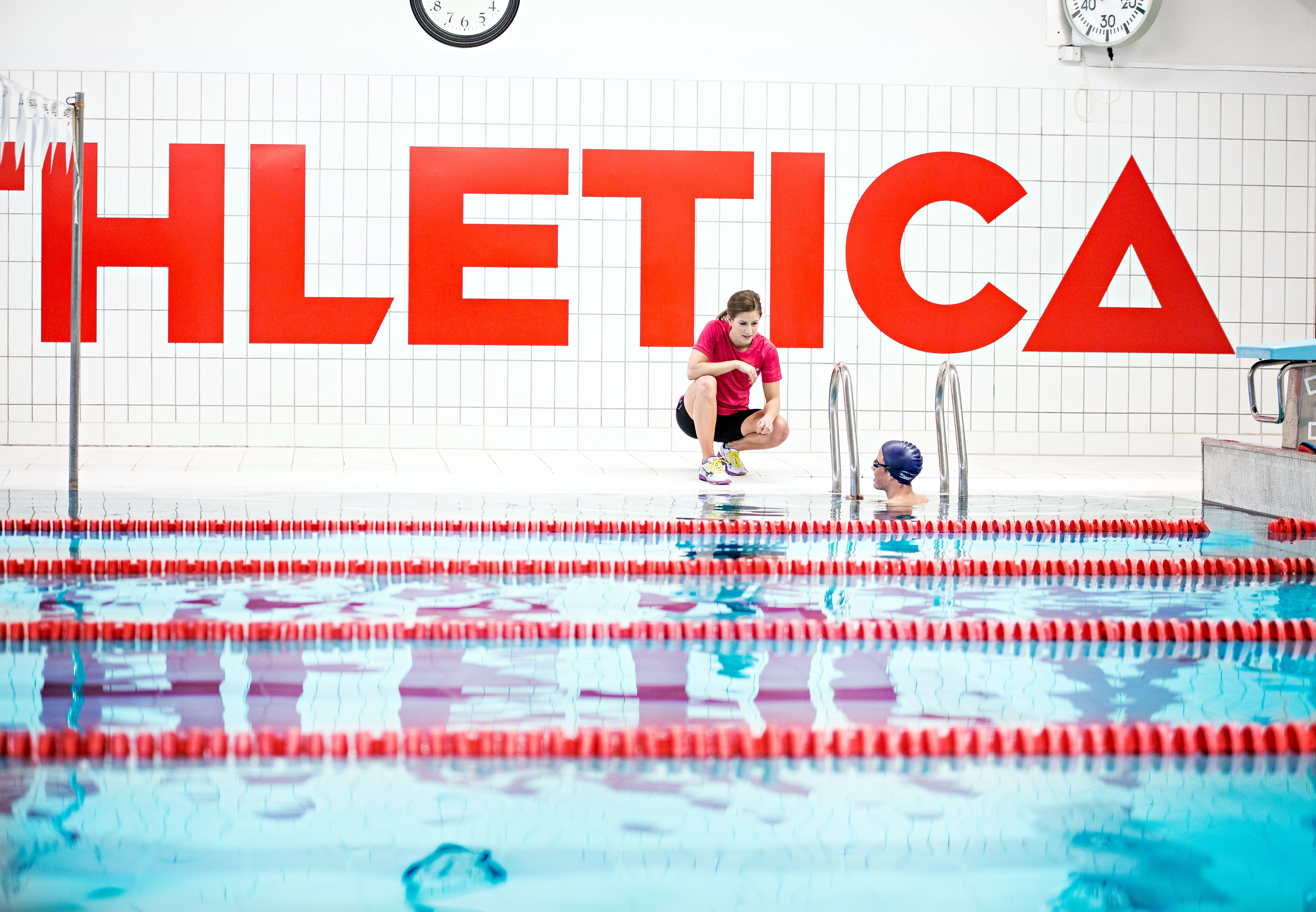 Svømmebasseng på Athletica Domus med en PT og en kunde som snakker sammen.