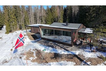 Foto av studenthytte med flagg foran, i natur med snøflekker.