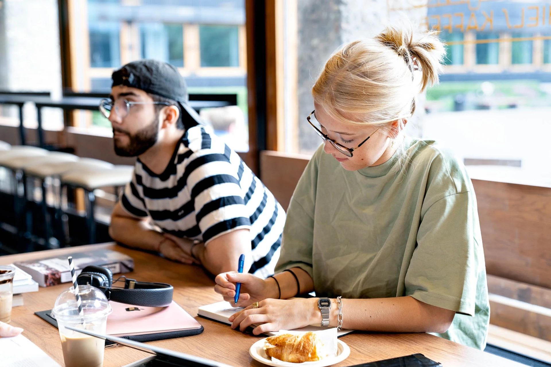 To studenter sitter og jobber med studiene på et spisested.