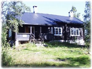 Foto med lav oppløsning av en tømmerhytte med hvite vinduer i natur.