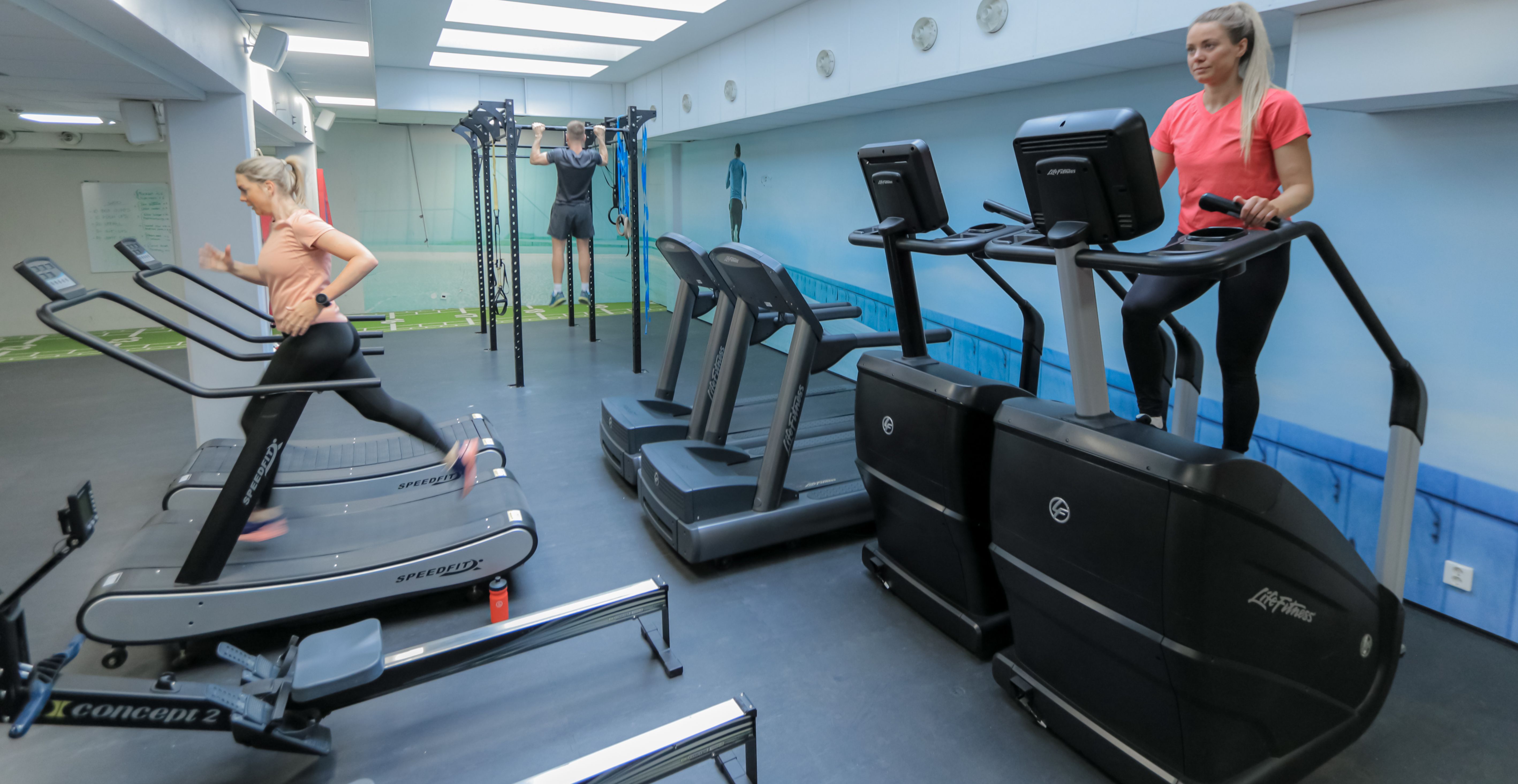 Tre stk som trener i kjelleren på Athletica Centrum, ved den funksjonelle cardiosonen. 