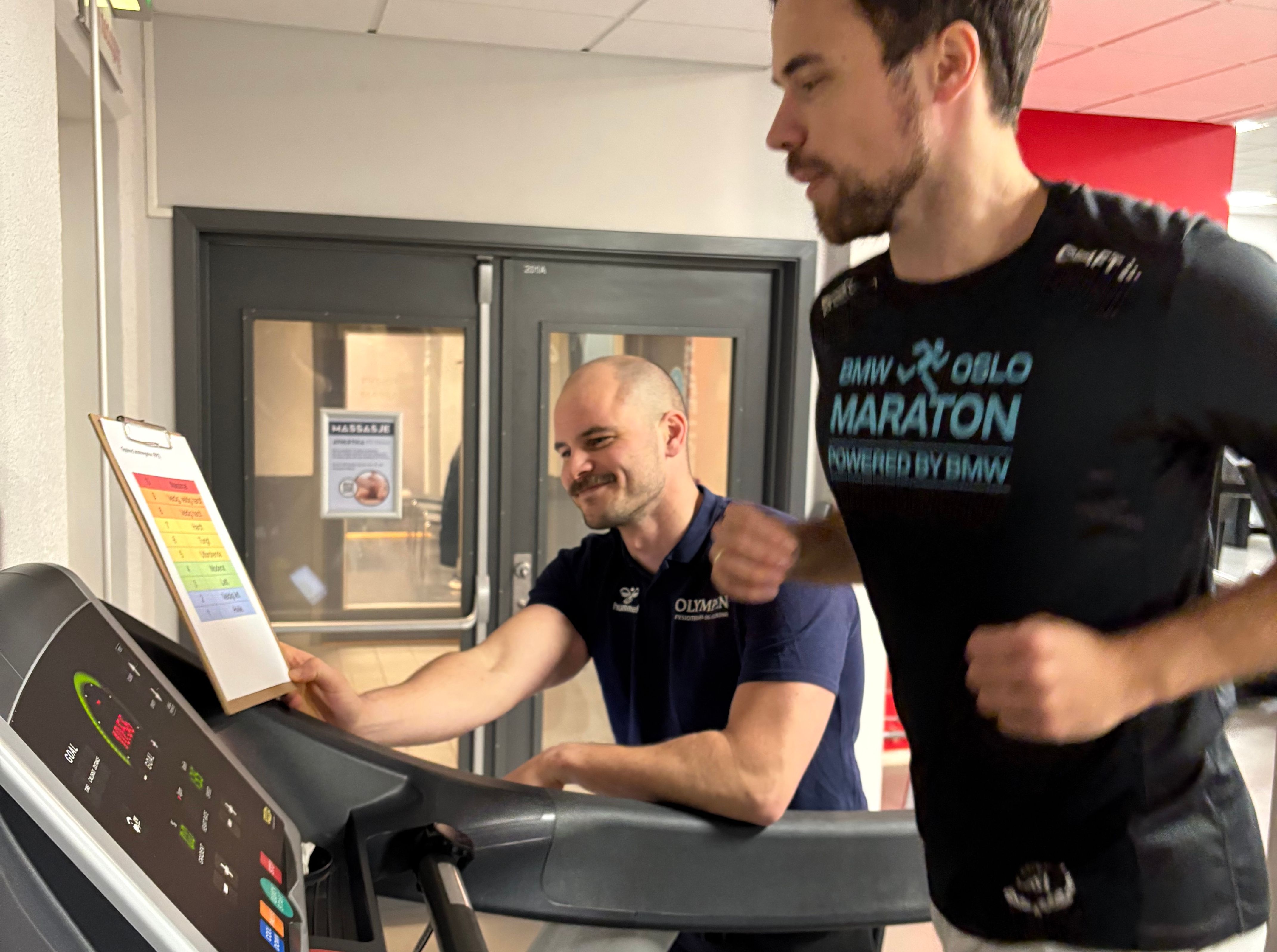 En fysioterapeut følger opp og trener en klient på tredemøllen. 