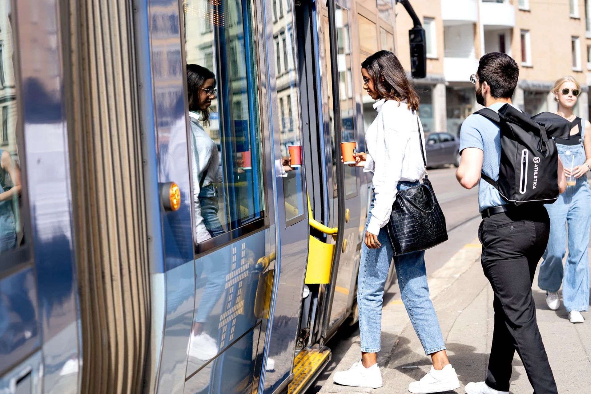 To studenter går på en blå trikk i Oslo sentrum.