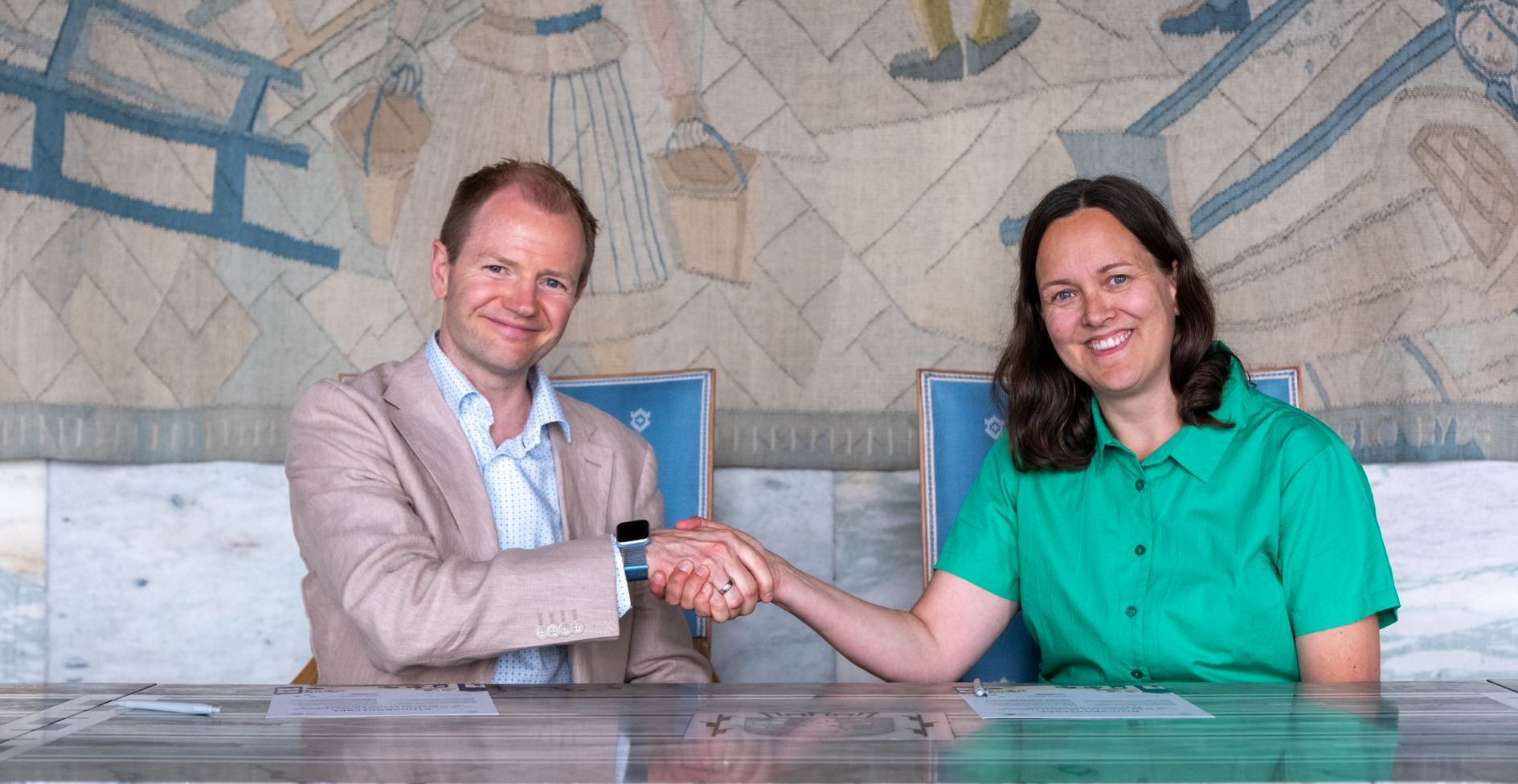 Foto av SiOs direktør og en kvinne som håndhilser og smiler.