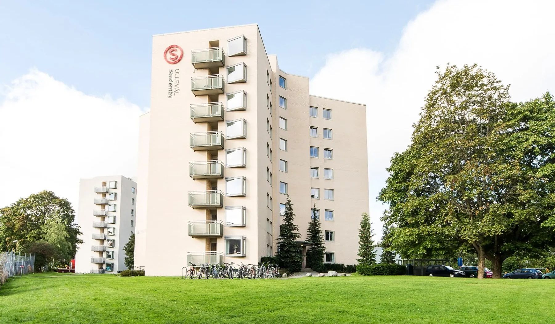 Foto av Ullevål Studentby, lys blokk med balkonger, i grønne omgivelser.