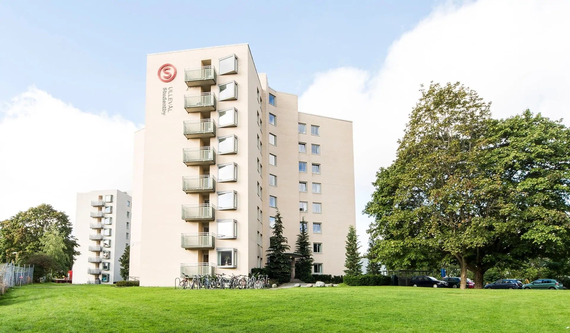Foto av Ullevål Studentby, lys blokk med balkonger, i grønne omgivelser.