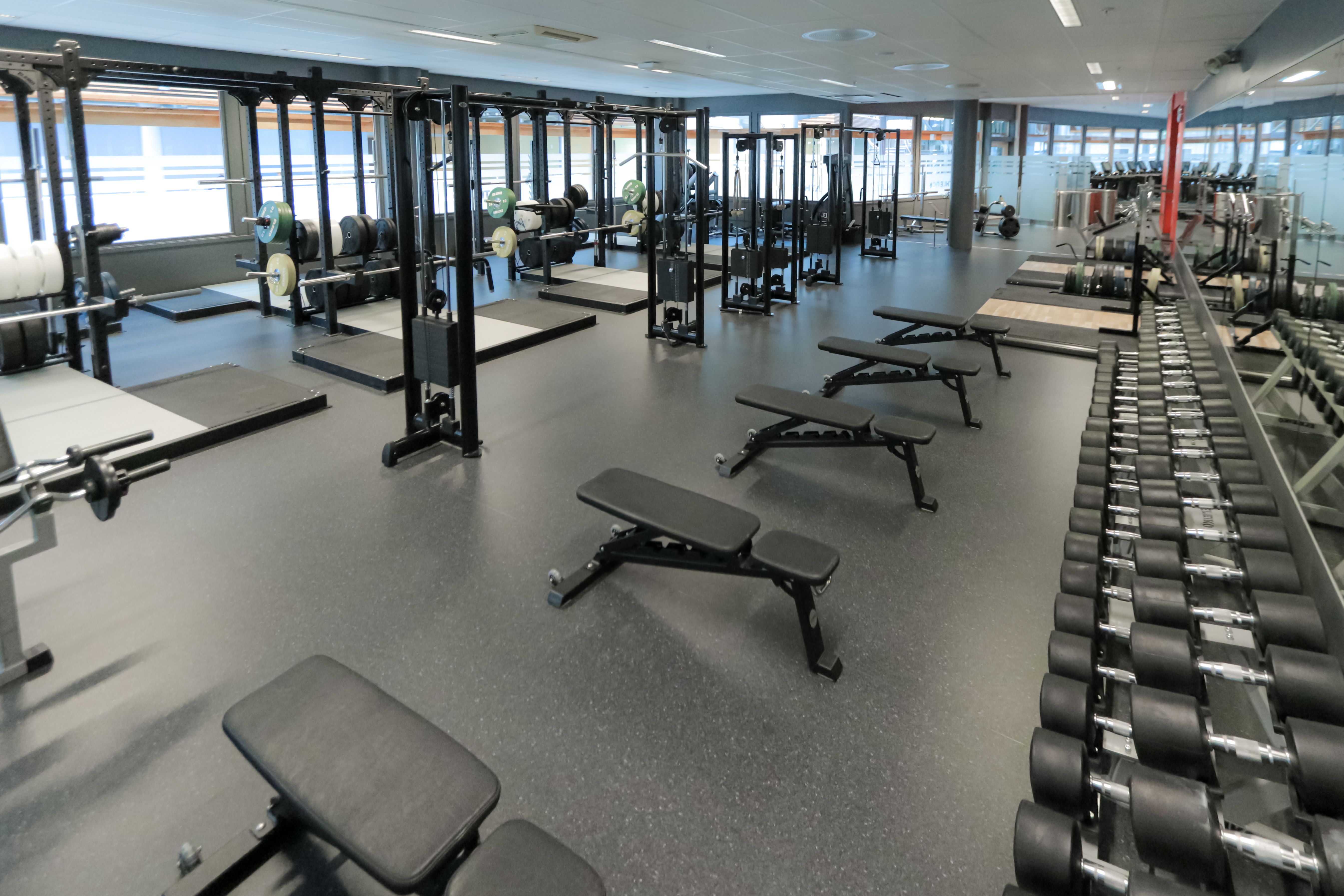 Bilde av studio hos SiO Athletica Nydalen, med benker og frivekter, løftestasjoner og kabeltrekk. 