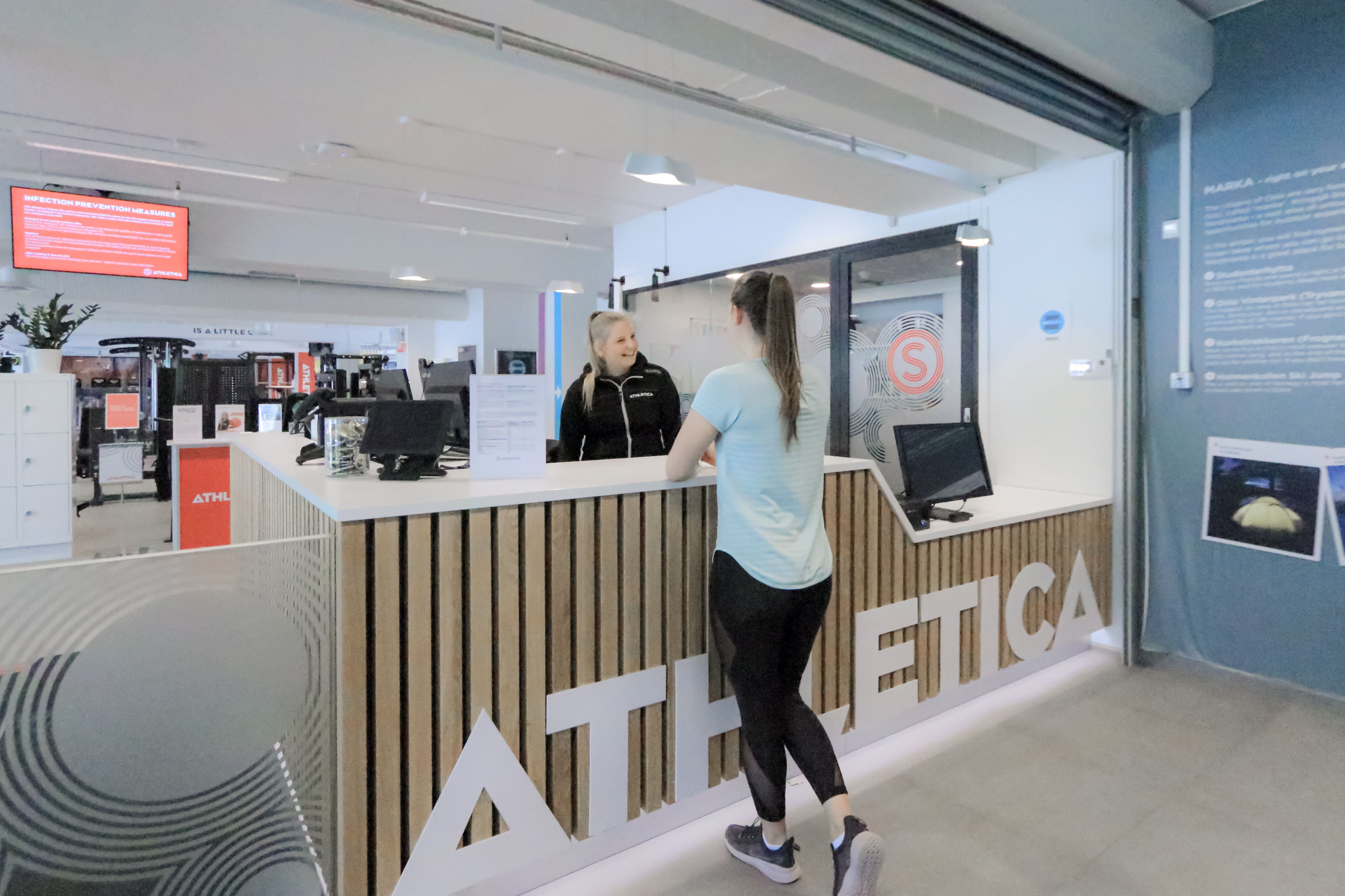 Resepsjonen på Athletica Kringsjå med en kunde og en ansatt. 