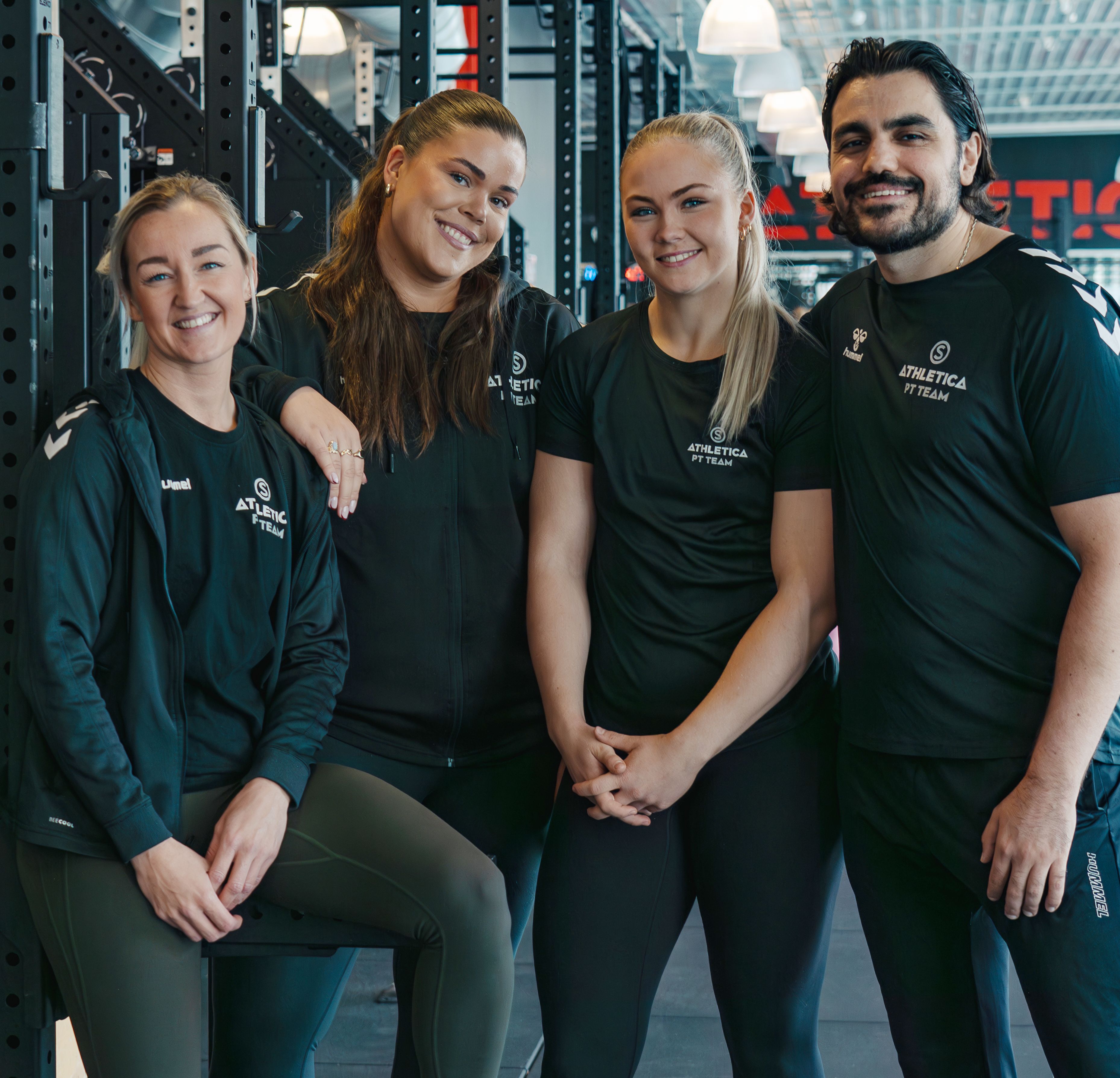 Bilde av fire ansatte ved Athletica Vulkan som smiler og er oppstilt i treningsstudio. 